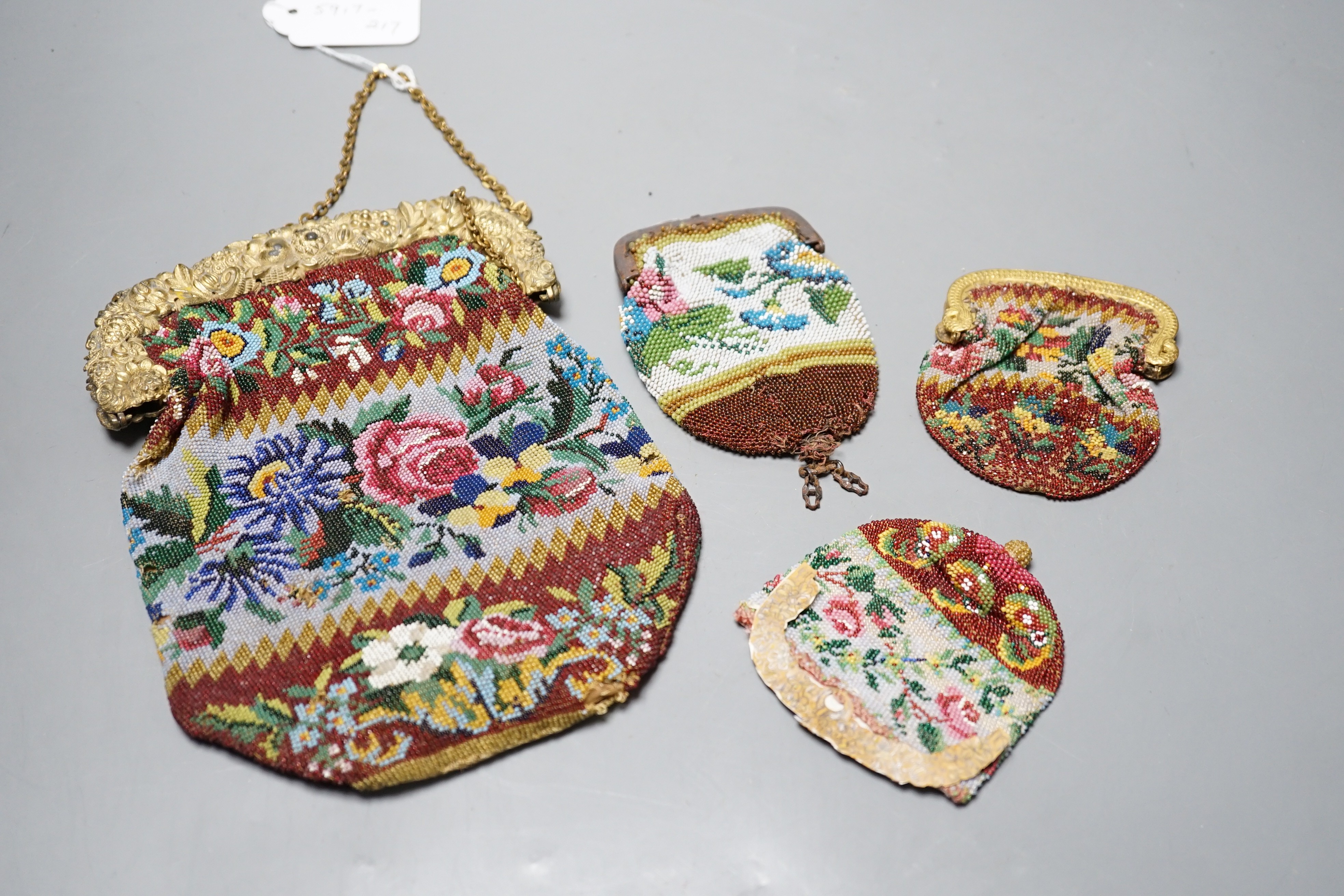 An early 19th century ornate gilt framed beaded bag with multi coloured floral design, together with three similar worked purses, gilt framed bag 20 cms high